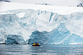 Touristen in einem Boot neben der gefrorenen Küstenlinie; Antarktis
