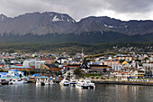 Boats In The Water At The Waterfront Of A City With Mountains In The Background; Ushuaia Argentina