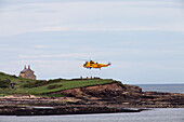 A Rescue Helicopter Taking Off From Land On The Water's Edge; Northumberland England
