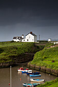 Small Boats In A Harbour Under Storm Clouds; England