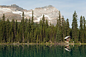 Cabin On Lakeshore Reflecting On Mountain See mit Berg im Hintergrund; Feld British Columbia Kanada