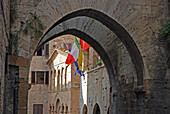Bögen in Mauerwerk und Fahnen am Rande eines Gebäudes; San Gimignano Italien