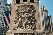 Skulptur an einer Wand mit Wolkenkratzern im Hintergrund vor einem blauen Himmel; Chicago Illinois Vereinigte Staaten Von Amerika