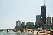 People In The Water And On The Beach With Skyscrapers In The Background; Chicago Illinois United States Of America