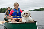 Zwei Mädchen in einem Kanu mit ihrem Haushund; Lake Of The Woods Ontario Kanada