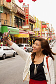 Eine Frau fotografiert sich selbst mit ihrer Handykamera in einem belebten Stadtgebiet; san francisco kalifornien vereinigte staaten von amerika