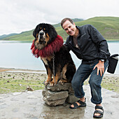 Man posing with Saint Bernard dog on shore of Sacred Lake; Shannan, Xizang, China