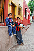 Mexiko, Bundesstaat Guanajuato, Guanajuato, Portrait von zwei Jungen mit Fußball in einer Gasse der alten spanischen Stadt