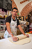 Young male baker rolling out pizza dough; Guanajuato, Guanajuato State, Mexico