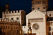 Italien, Trentino, Trento, Domplatz, beleuchteter Neptunbrunnen bei Nacht und Steinmauern von Dom und Palast im Hintergrund