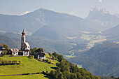 Kirche mit Zwiebelkuppelturm auf Wiese mit Bergen und Tälern im Hintergrund; Bozen, Dolomiten, Südtirol, Italien
