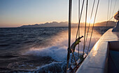 Boat splashing through water along Lycian coast at sunset; Turkey
