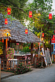 Thailand, Lanterns hanging over street lined with retail shops; Pai