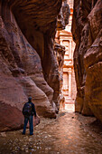 Jordan, Man looking at El Khazneh seen from natural narrow canyon; Petra