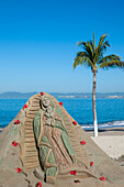 Mexico, Puerto Vallarta, Sand sculpture with religious message located on beach; Banderas Bay