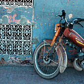 Ein altes Motorrad, geparkt an einer verwitterten Mauer; Marrakesch, Marrakesch-Tensift-El Haouz, Marokko