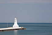 Kleiner weißer Leuchtturm am Ende eines Piers in einem See mit blauem Himmel; Burlington, Ontario, Kanada