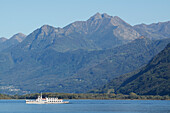 A Boat In Lake Maggiore With The Swiss Alps In The Background; Locarno, Ticino, Switzerland
