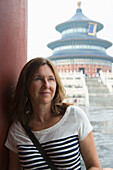 Eine Frau lehnt sich an eine Mauer mit dem Himmelstempel im Hintergrund; Peking, China