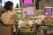 A Cashier Weighs Fresh Produce On A Scale And Chooses A Button On The Screen At Checkout; Ascona, Ticino, Switzerland