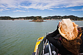 Ein Mädchen hält ihren Cowboyhut auf einer Bootsfahrt von Russell nach Paihia; Neuseeland