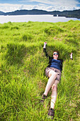 Ein Mädchen entspannt sich im dichten weichen Gras auf Urupukapuka Island; Bay Of Islands, Neuseeland