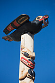Animals Carved And Painted On A Wooden Totem Pole Against A Blue Sky; Whitehorse, Yukon, Canada
