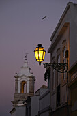 Glockenturm der Igreja de Santo Antonio und Straßenlampe in der Abenddämmerung, Lagos, Portugal