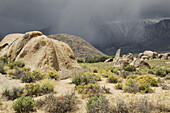 Rock formations of the Alabama Hills with storm clouds over the Sierra Nevada Mountains in the background in Eastern California, USA