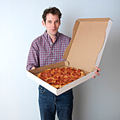 Portrait eines Mannes, der eine Pizza hält