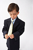 Little Boy Dressed Up as a Businessman Looking at His Tie