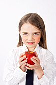 Mädchen in Schuluniform hält Apfel