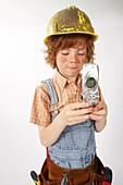 Junge als Bauarbeiter verkleidet benutzt Handy