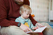 Vater liest Kind mit Down-Syndrom ein Buch vor