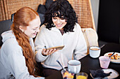 Junge Frauen telefonieren und lachen bei einem Video im Cafe