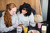 Lächelnde junge Frau mit Telefon und Blick auf soziale Medien in einem Cafe