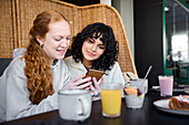 Lächelnde junge Frau telefoniert im Cafe