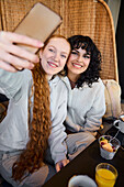 Lächelnde junge Frauen machen ein Selfie im Cafe