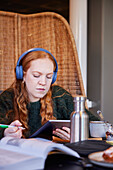 Young woman wearing headphones and studying