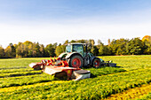 Traktor mäht Gras auf einer Wiese