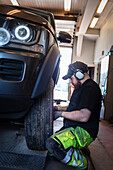 Mechanic in garage changing tires on car