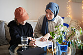 Mutter trägt Hijab und hilft Sohn bei den Hausaufgaben