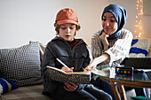 Mother wearing hijab helping son doing homework