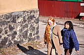 Freundinnen beim gemeinsamen Spaziergang im Freien auf einem Gehweg in der Stadt
