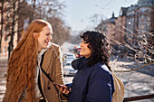 Female friends listen to music or podcast while sharing in-ear headphones