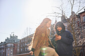 Freundinnen schauen auf ihr Handy im Freien mit Sonne im Hintergrund