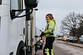 Female road worker standing next to truck