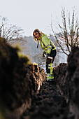 Junge Arbeiterin gräbt einen Graben