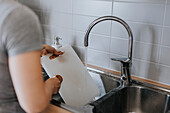 Frauenhände waschen Geschirr in der Spüle