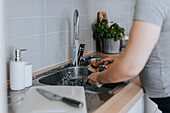 Woman's hands washing dishes in kitchen sink